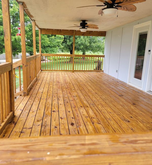 A large wooden deck with a ceiling fan