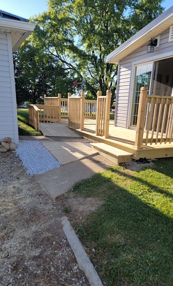 A wooden deck is sitting next to a white house.