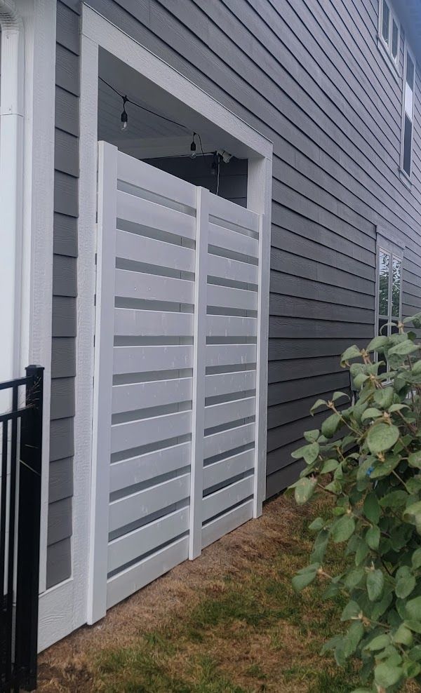 A white fence is sitting in front of a gray house.