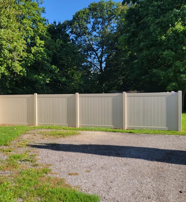 A white fence surrounds a grassy area with trees in the background.