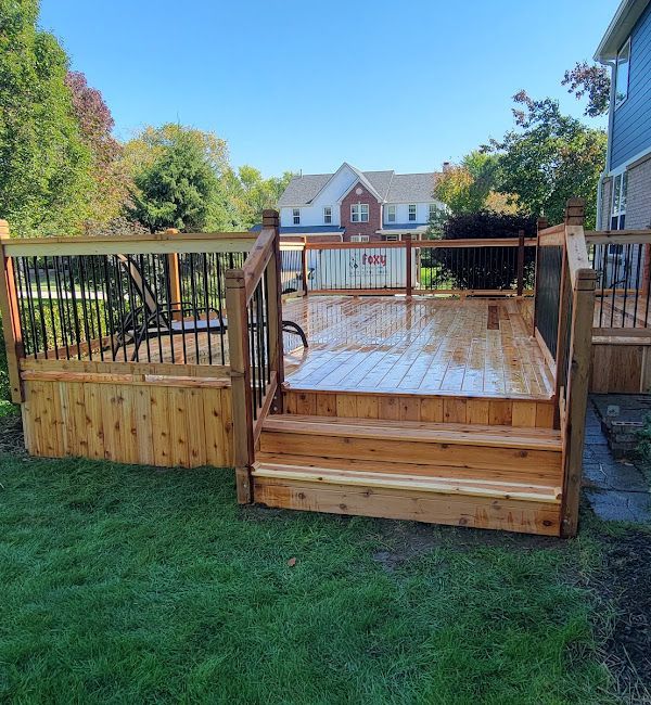 A wooden deck with stairs and a fence in the backyard of a house.