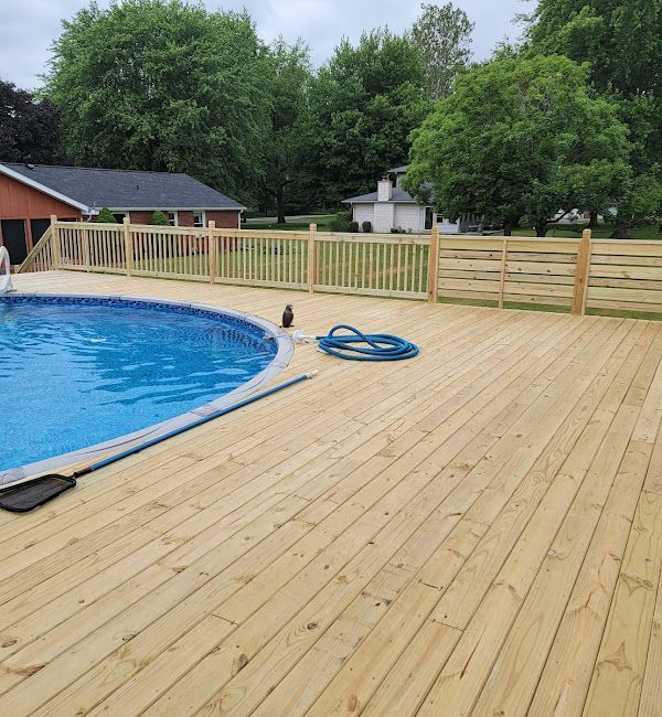 A wooden deck with a swimming pool in the background.