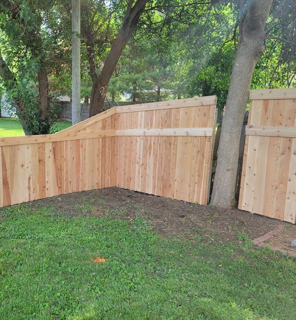 A wooden fence is sitting in the middle of a lush green yard.