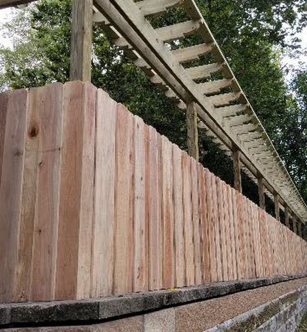 A wooden fence with a railing and trees in the background.