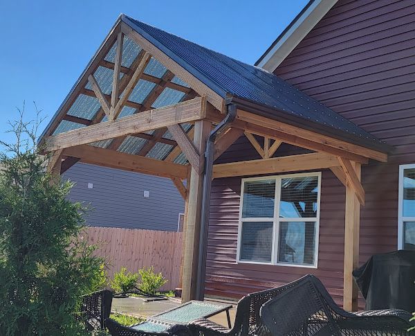 A red house with a wooden porch and a table and chairs underneath it.