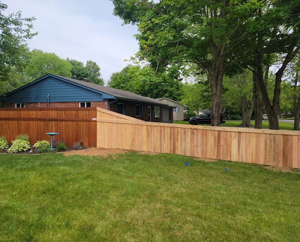A wooden fence is in the backyard of a house.