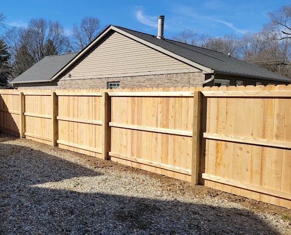 A wooden fence is in front of a house.
