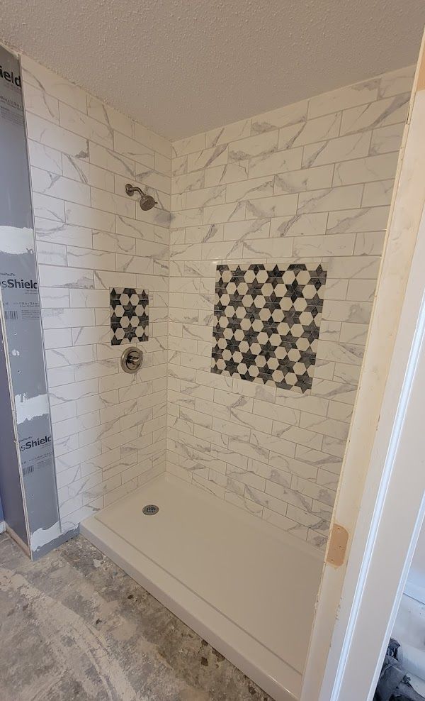 A bathroom with a walk in shower and a tiled wall.