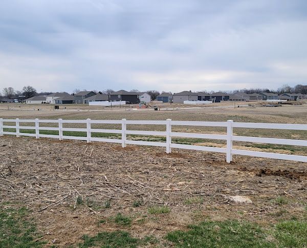 There is a white fence in the middle of a field.