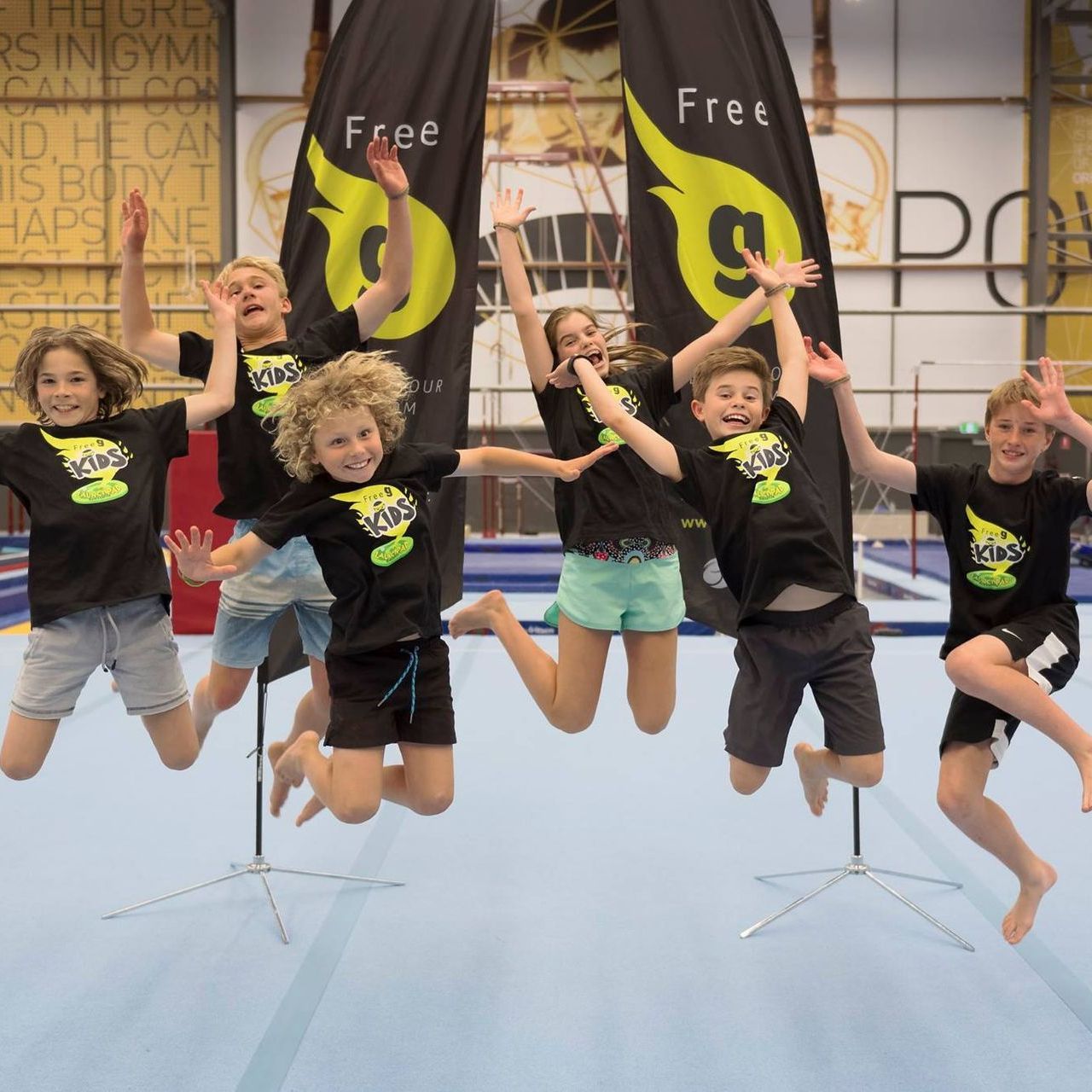 A group of kids are jumping in the air in front of a sign that says free