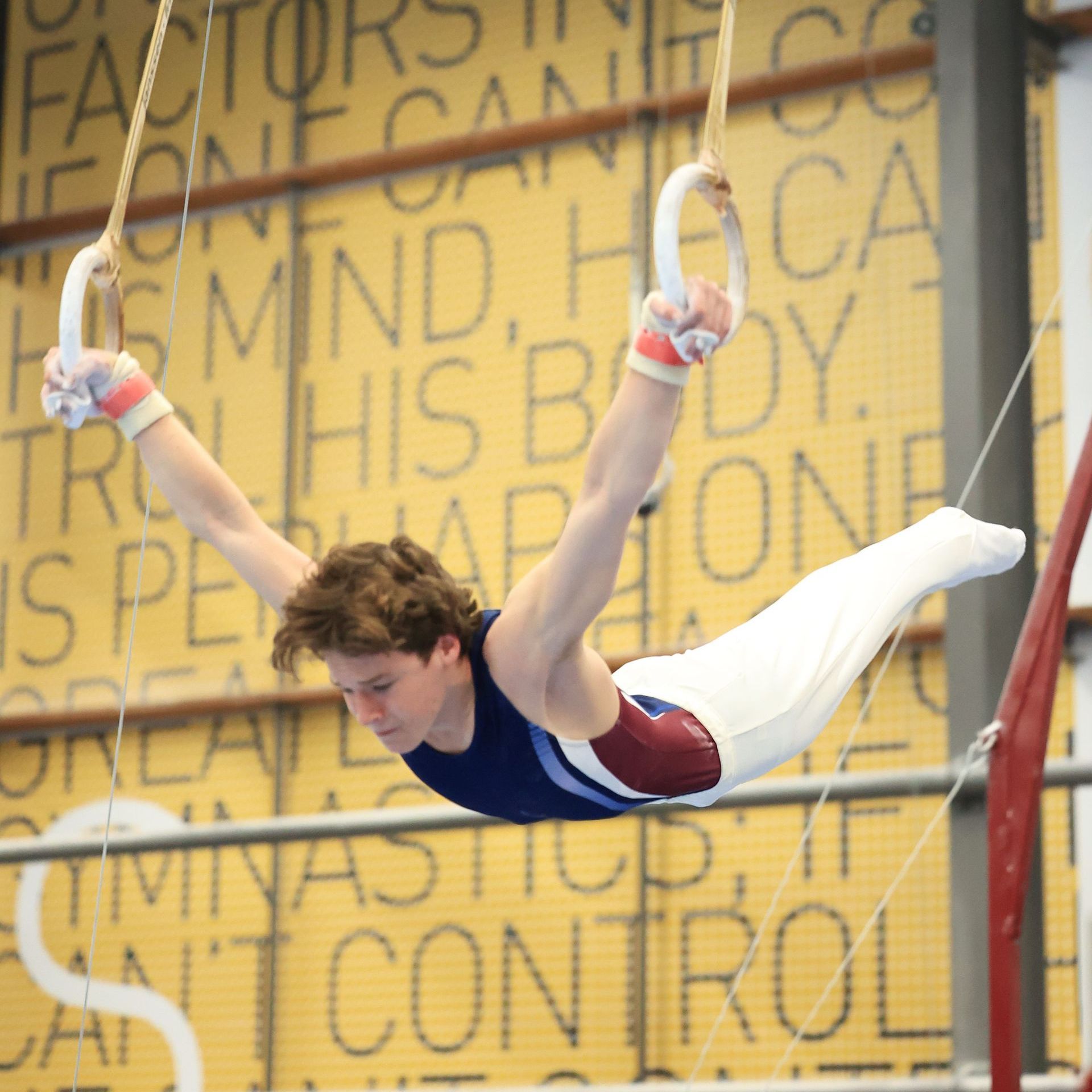 A man is doing a handstand on a bar in a gym