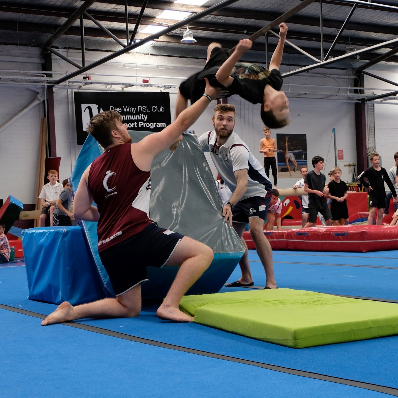 A group of people are doing gymnastics in a gym with a sign that says community