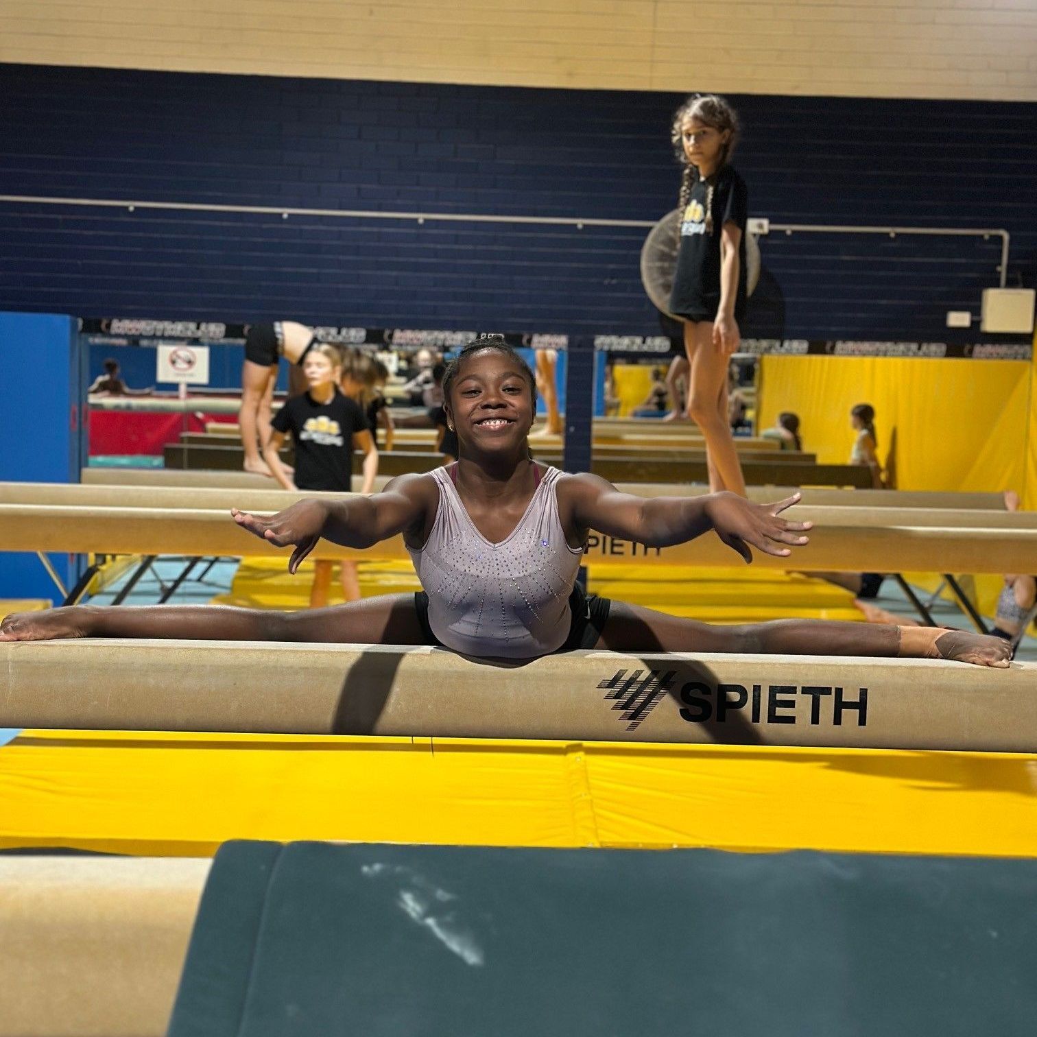 A girl is doing a split on a srieth balance beam