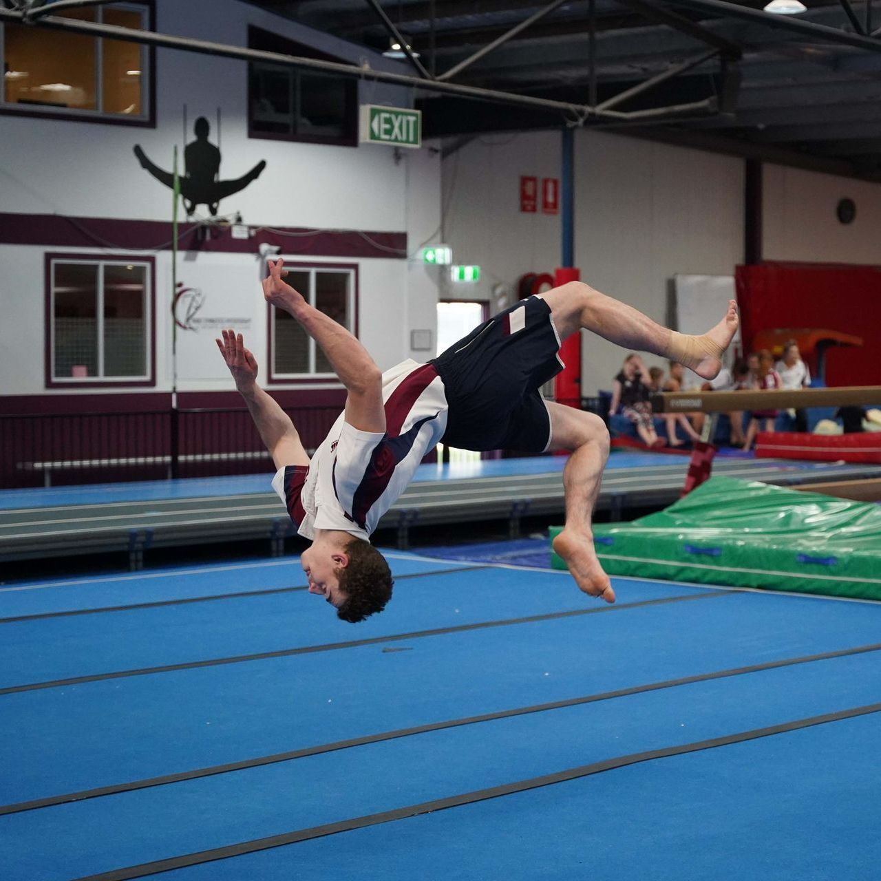 A man is doing a handstand on a balance beam