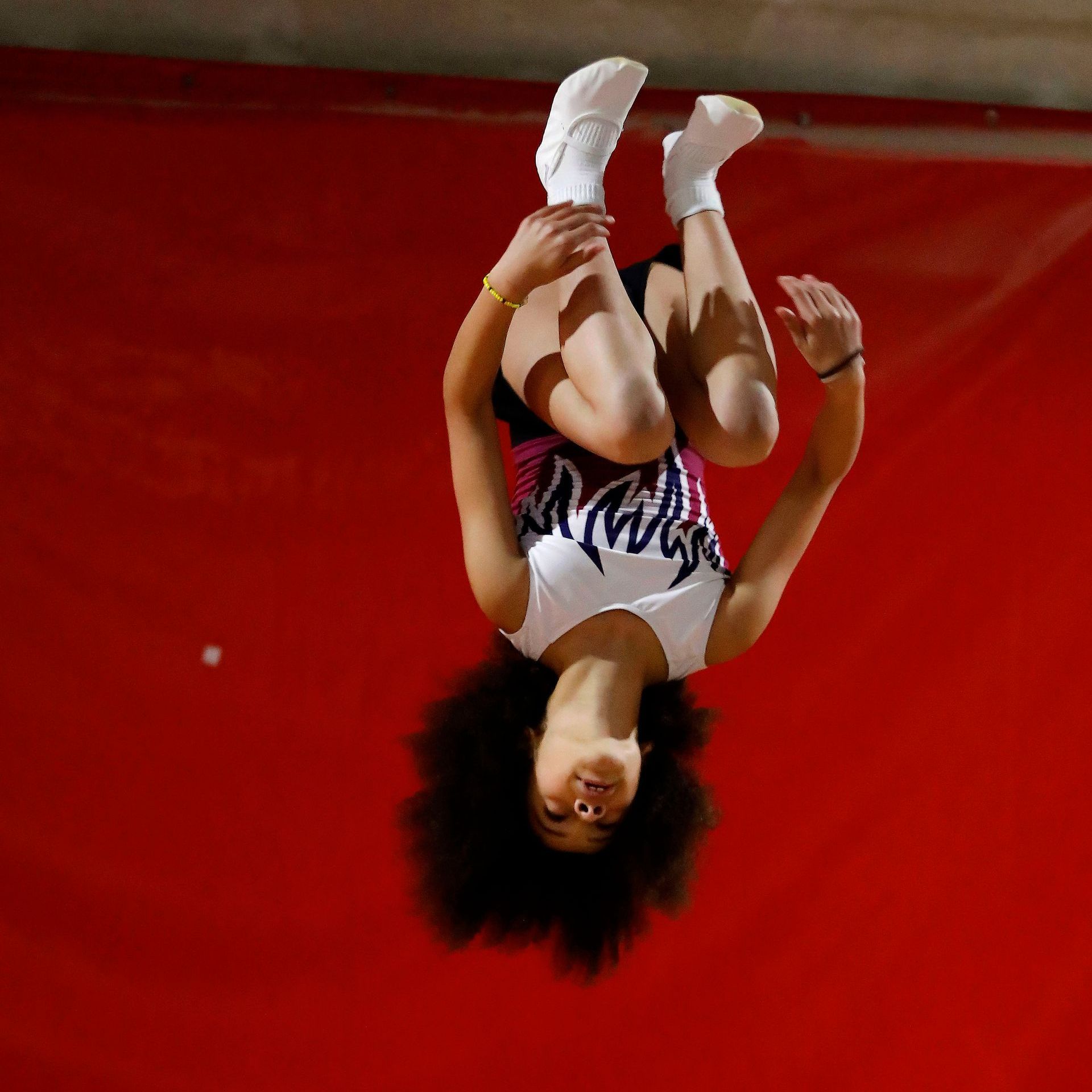 A woman is doing a handstand on a red mat