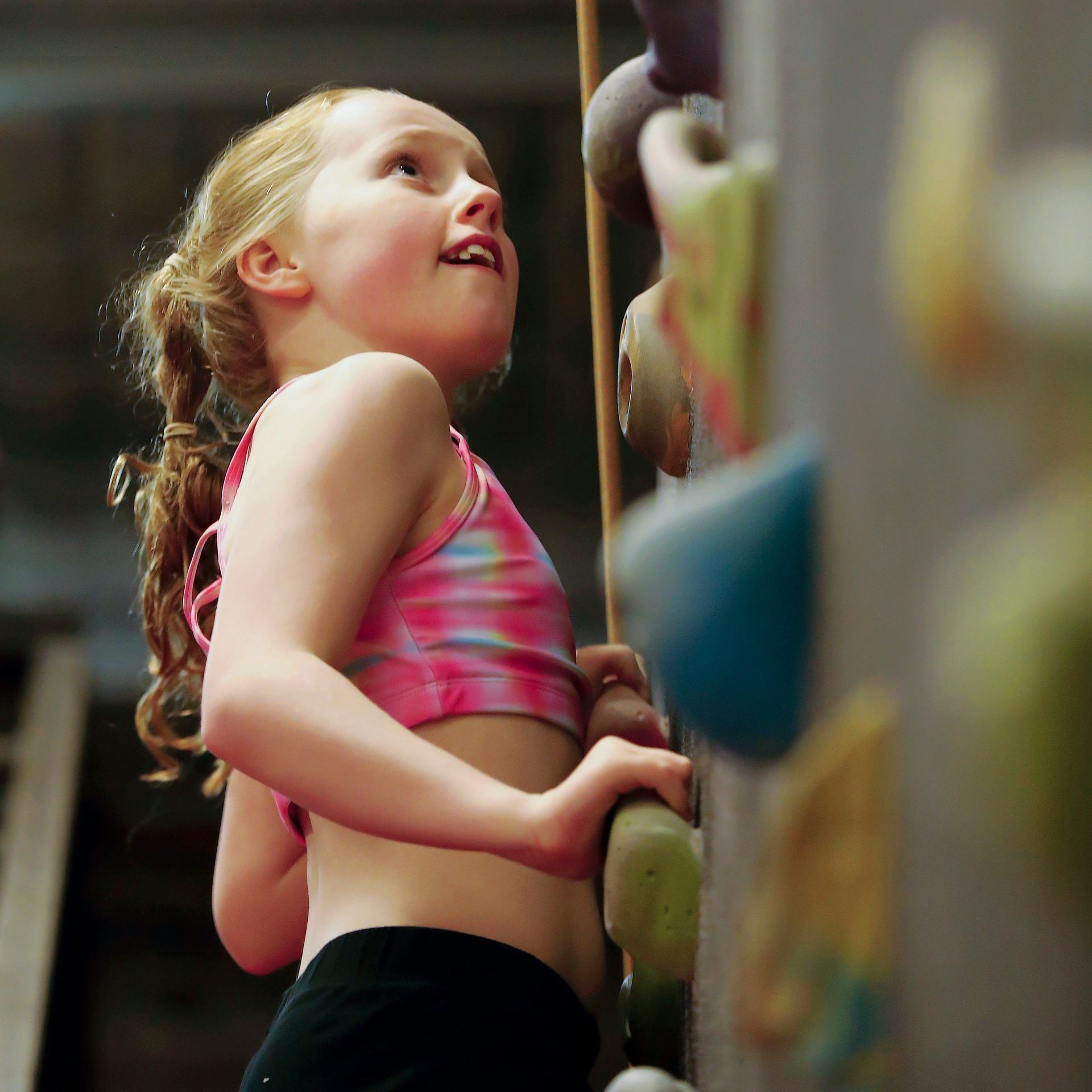 A little girl is climbing up a climbing wall