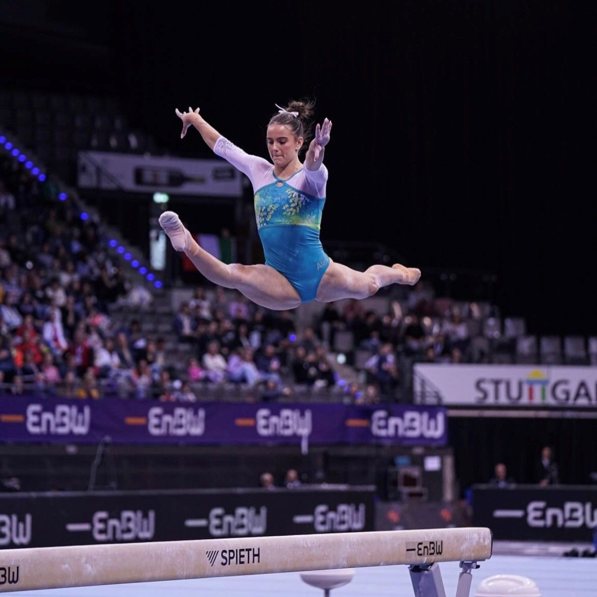A girl is doing a split on a srieth balance beam