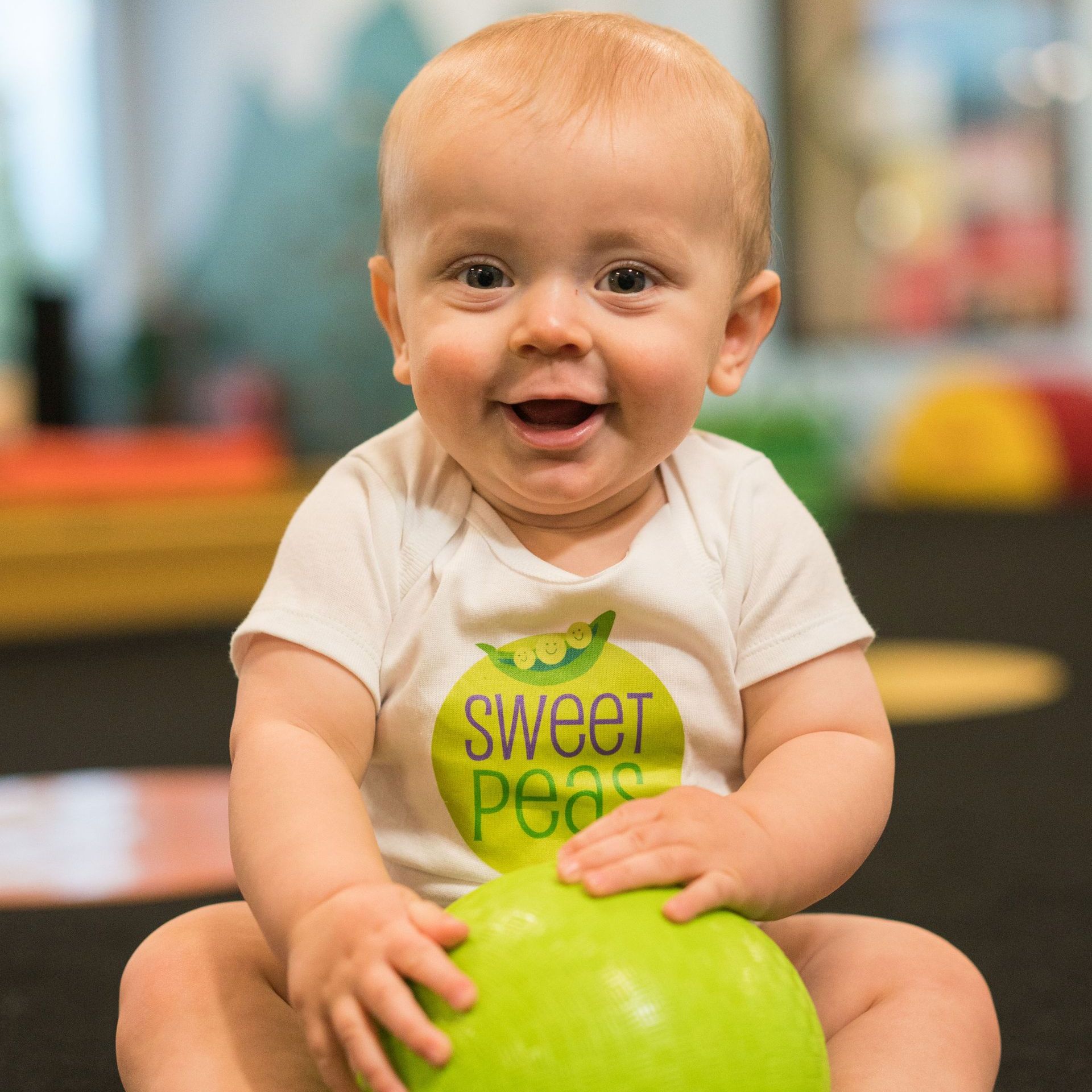 A little girl wearing a shirt that says sweet peas is sitting on a swing