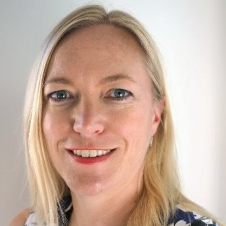 A woman with blonde hair and blue eyes is smiling for the camera.