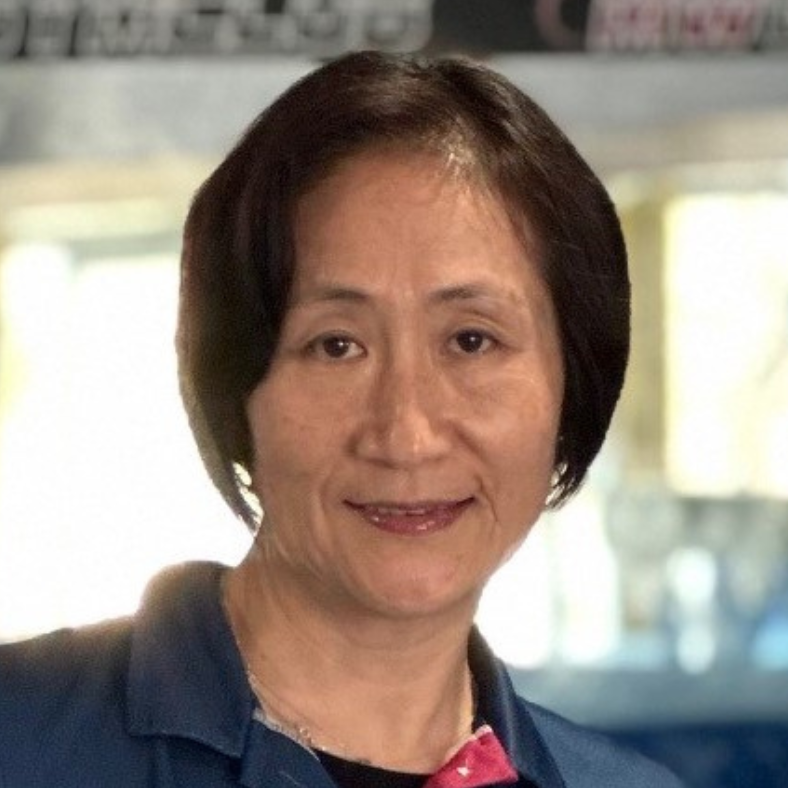 A woman in a blue shirt is smiling for the camera.