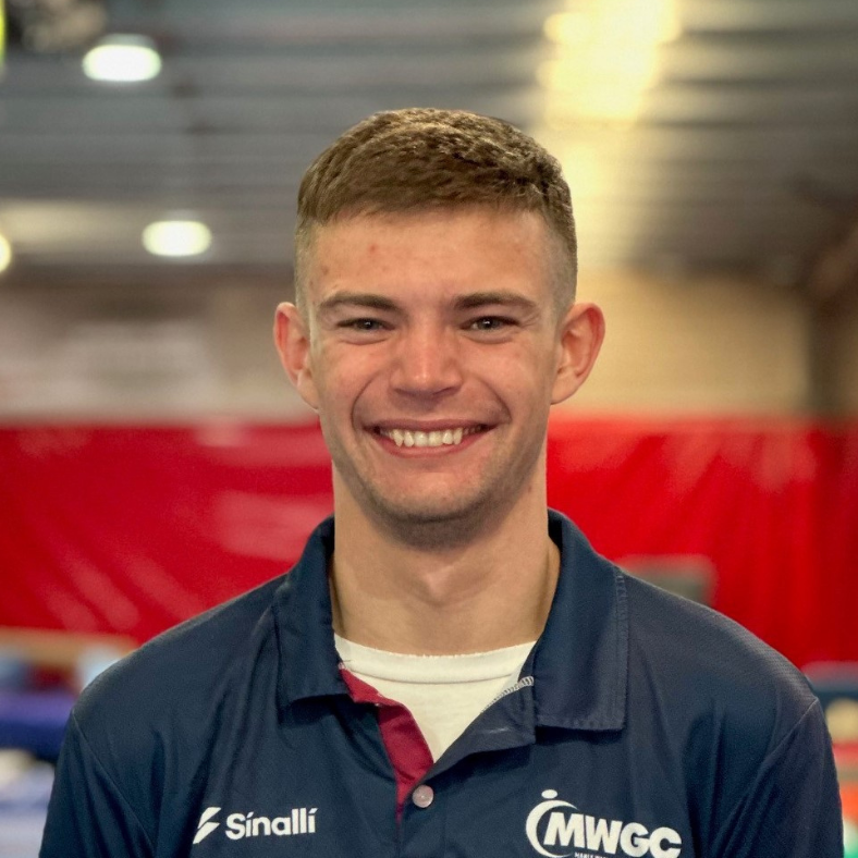 A young man in a blue shirt is smiling for the camera.