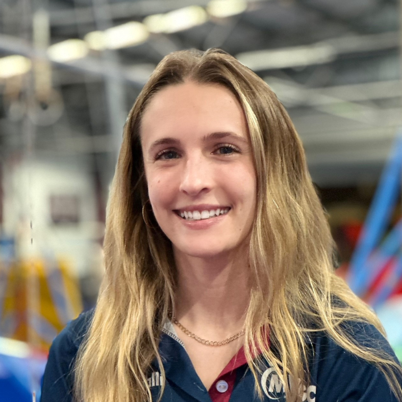 A young woman is smiling for the camera in a gym.