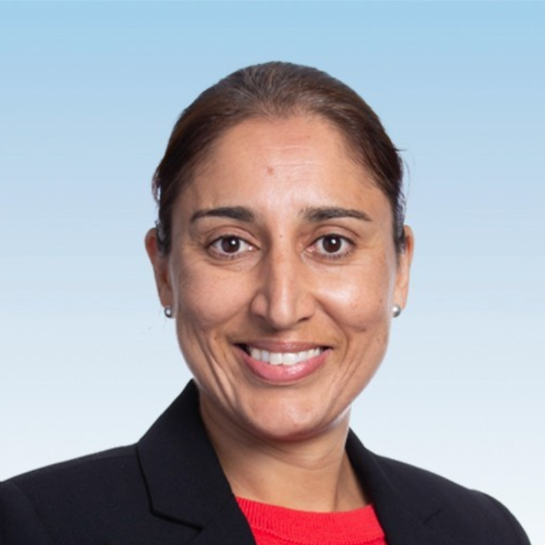 A woman in a black jacket and red shirt smiles for the camera