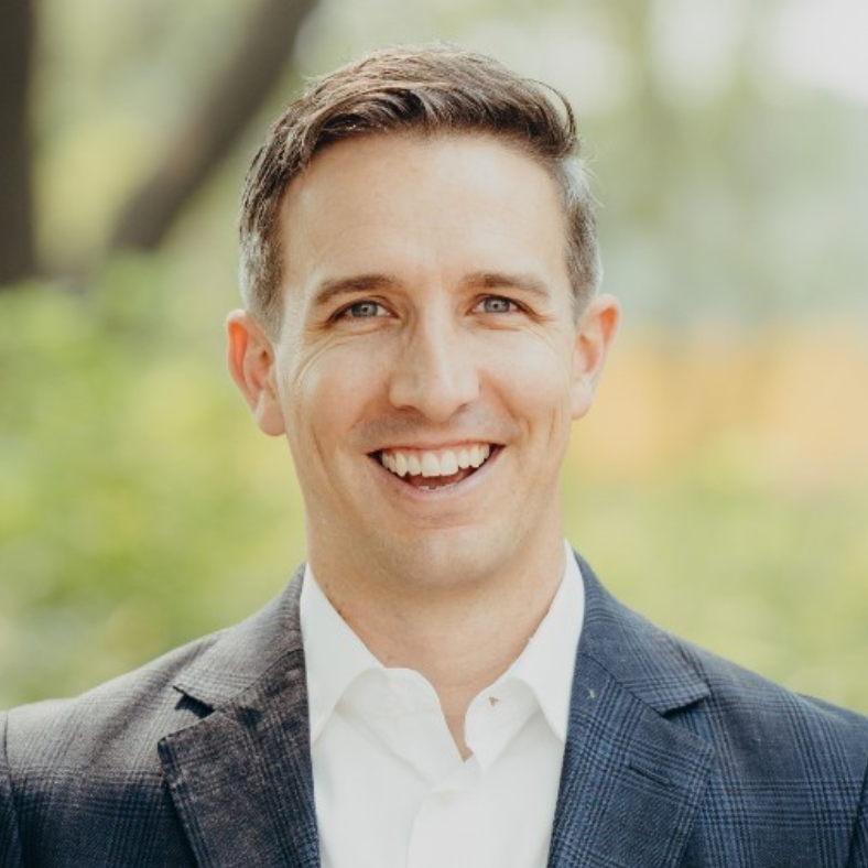 A man in a suit and white shirt is smiling for the camera.