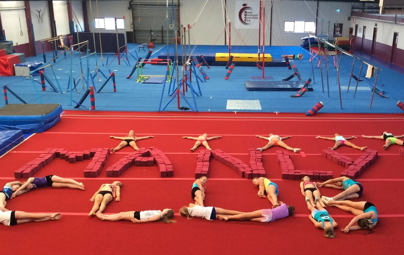 A group of girls are laying on the floor in a gym.