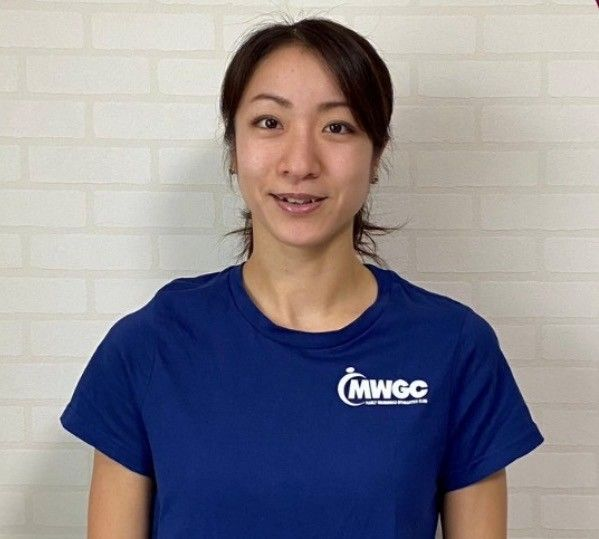 A young woman in a blue shirt is standing in a gym.
