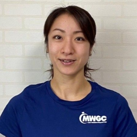 A young woman in a blue shirt is standing in a gym.