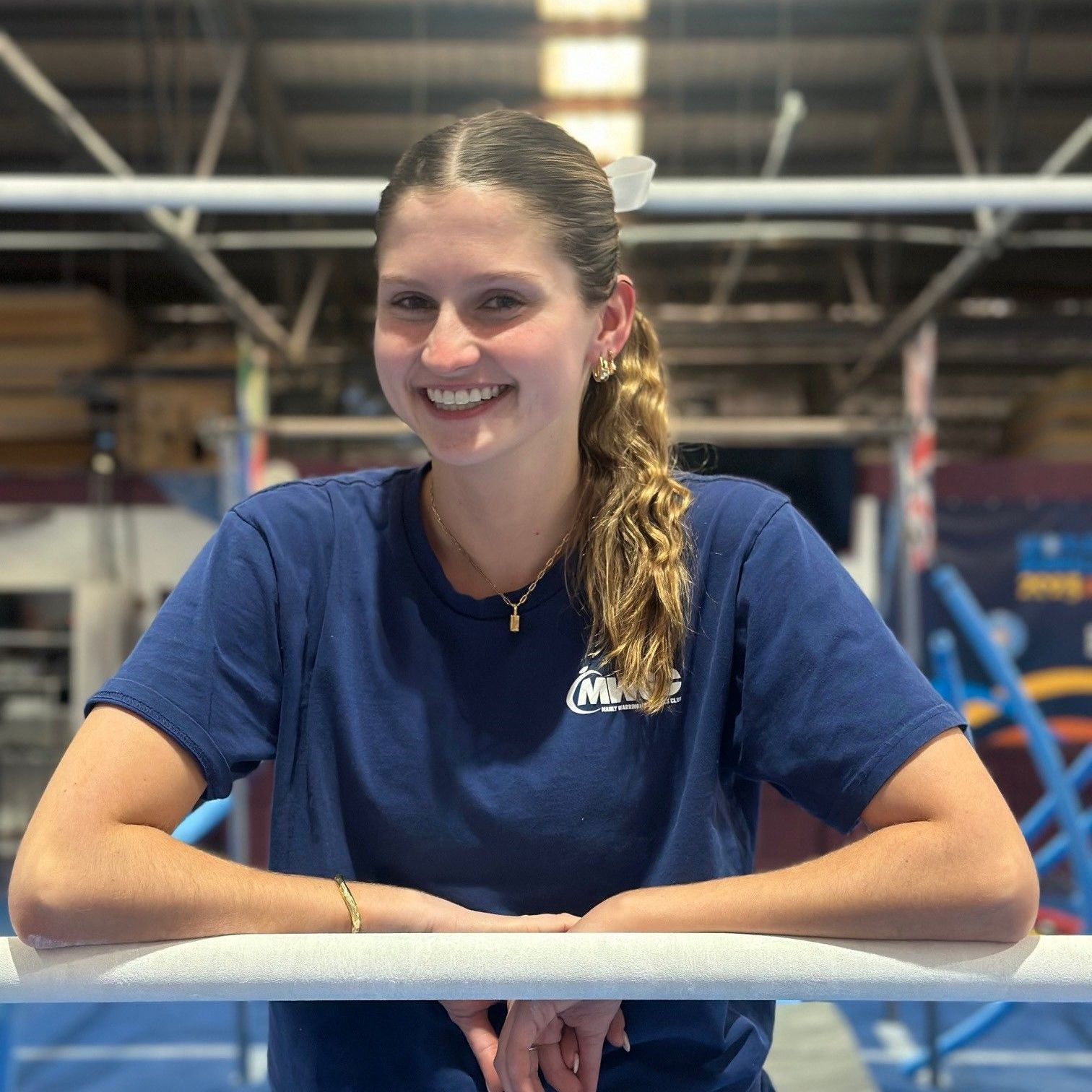 A young woman in a blue shirt is smiling for the camera.