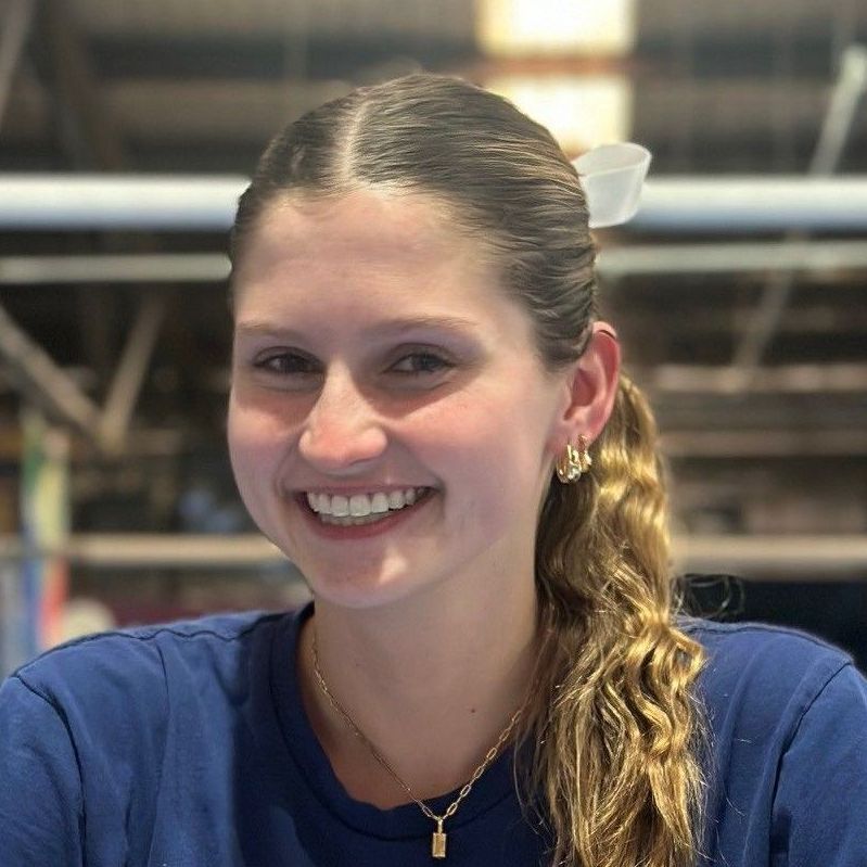 A young woman in a blue shirt is smiling for the camera.
