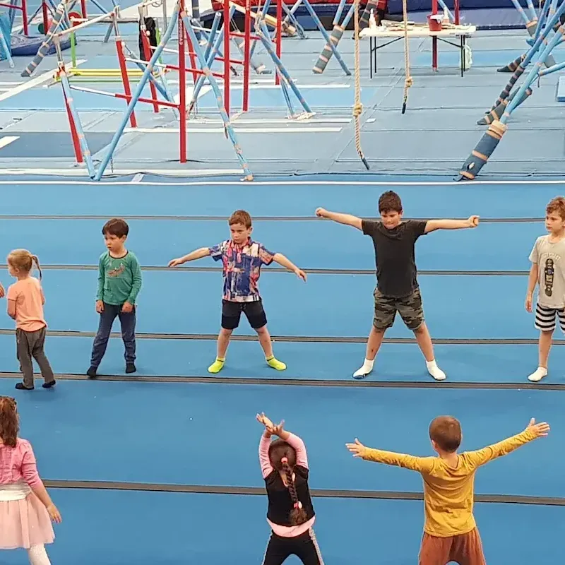 A group of children are doing exercises on a blue floor