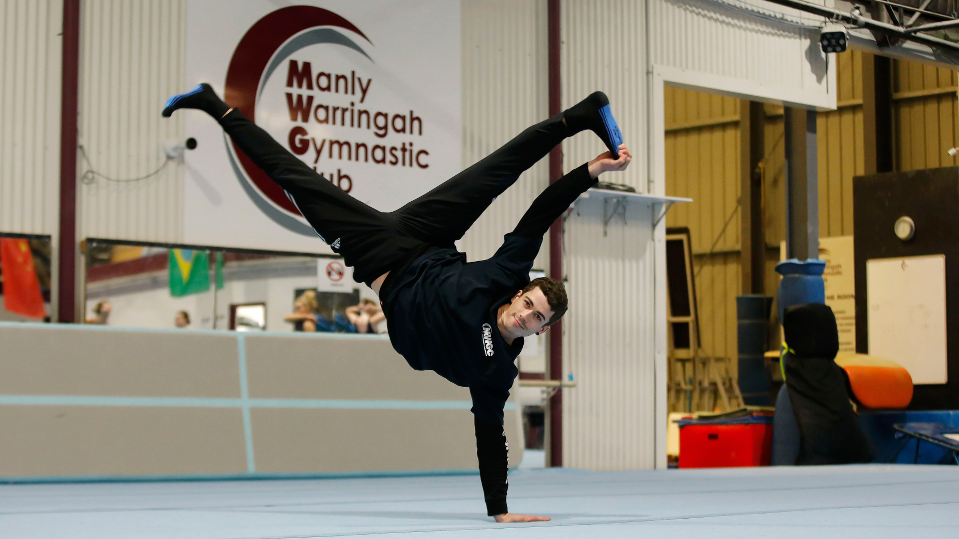 A man is doing a handstand on a gym floor.