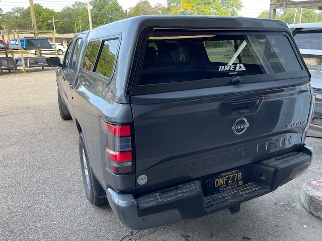 Dark gray Nissan Titan pickup truck with a camper shell in a parking lot.
