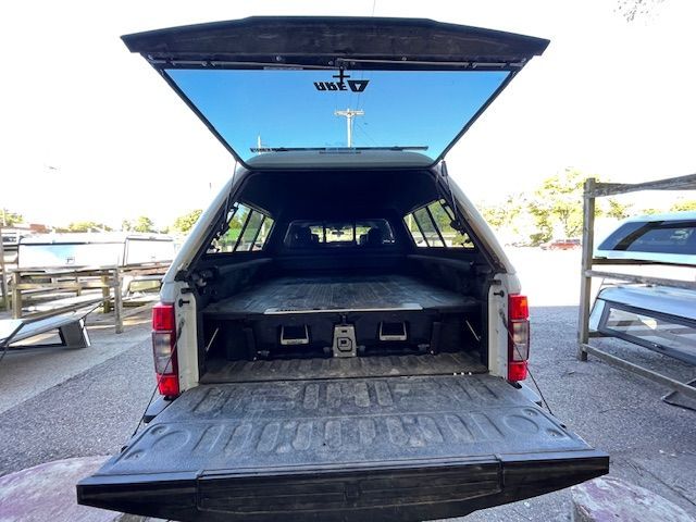 Truck bed with open tailgate and camper shell, revealing a black storage system.