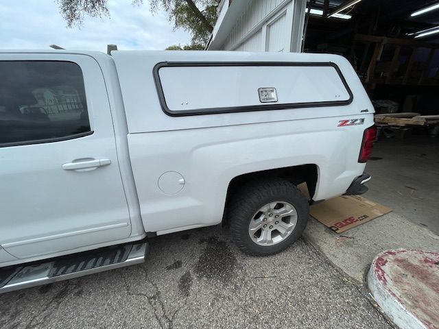 White pickup truck with a matching camper shell parked outside.