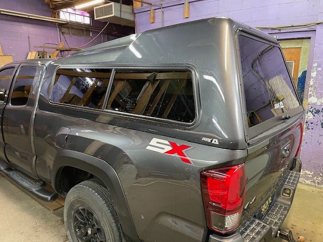 Gray pickup truck with matching camper shell, indoors. 