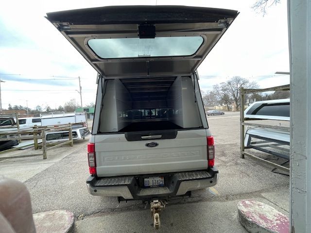 Silver pickup truck with camper shell, tailgate open, showing the interior space.