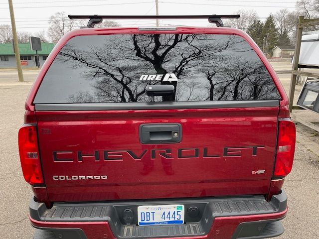 Red Chevrolet Colorado truck with a camper shell, and a roof rack.