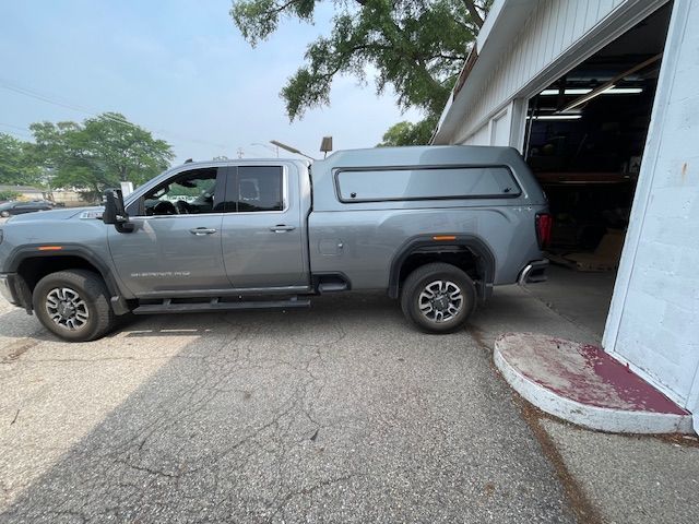 Gray pickup truck with camper shell parked next to a building.