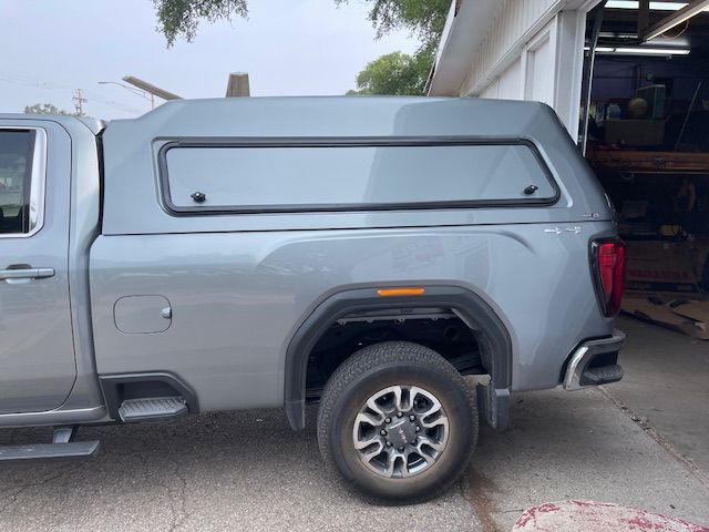Gray truck with matching camper shell parked outside a building.