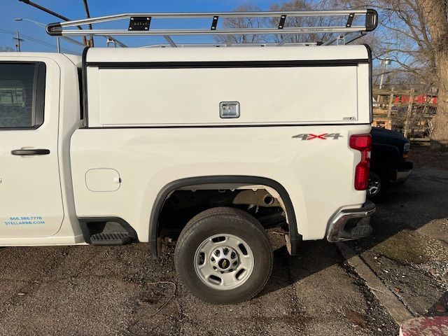 White work truck with a ladder rack and utility box, parked outdoors.