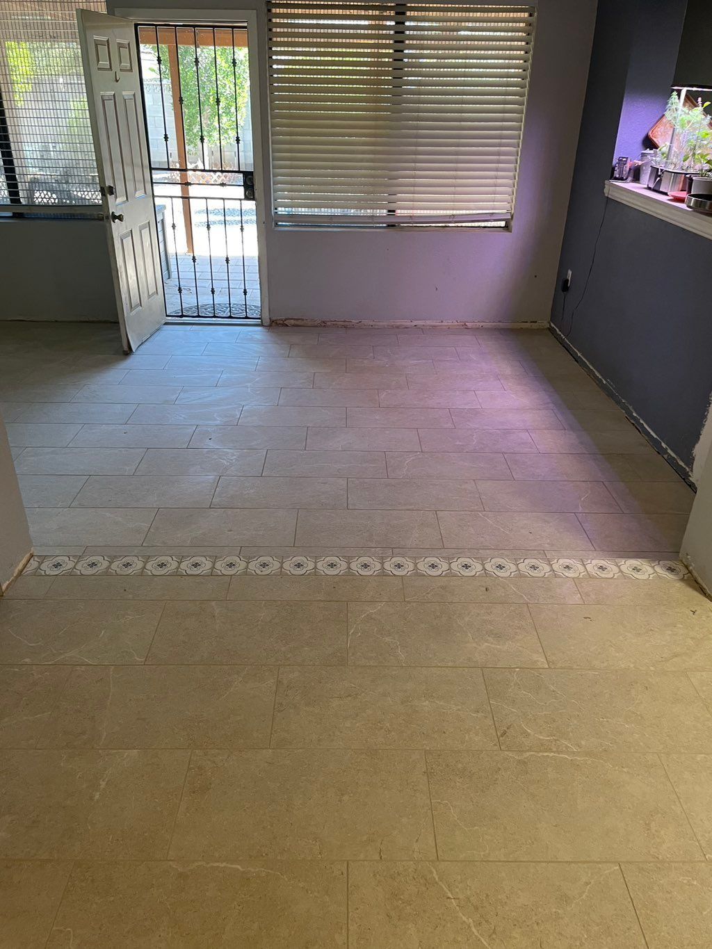 Empty room with light-colored flooring, open door, and window with blinds.