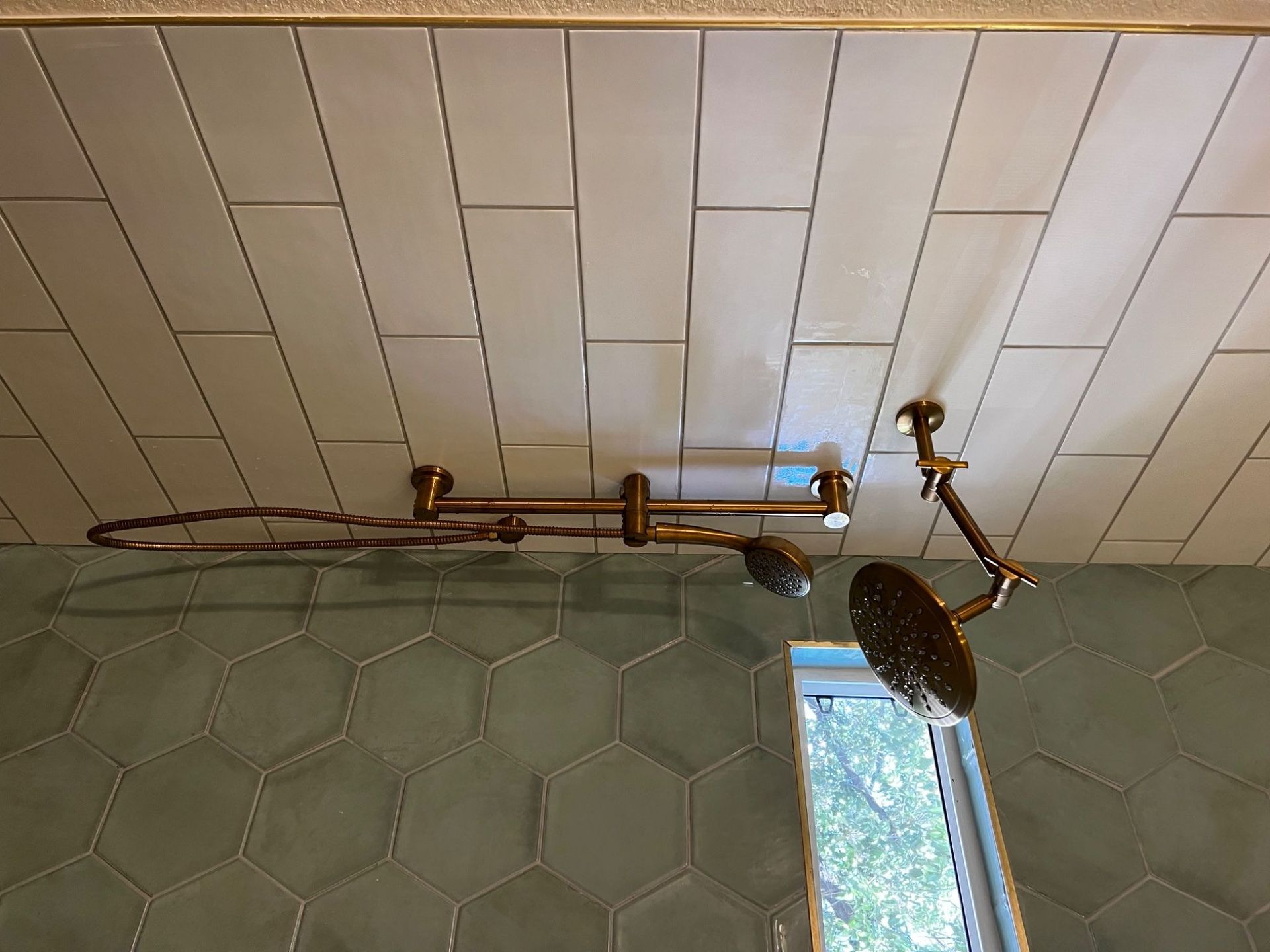 Gold shower fixtures against white and green tiled walls.