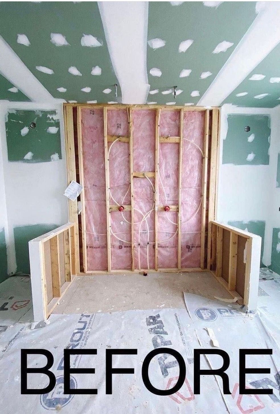 Framed-out wall section in construction phase with insulation and exposed studs. The word 