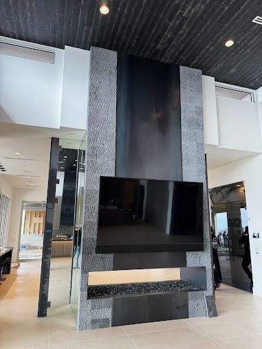 Modern fireplace with TV, gray stone, black metal, and floating shelf.