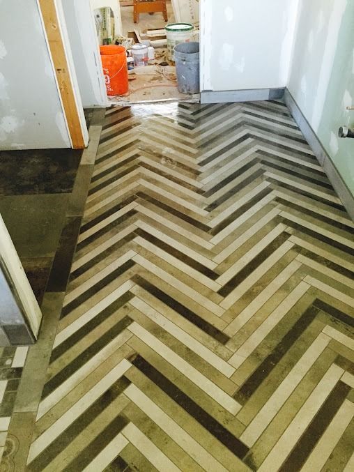 Herringbone pattern floor in shades of brown and tan in a hallway.