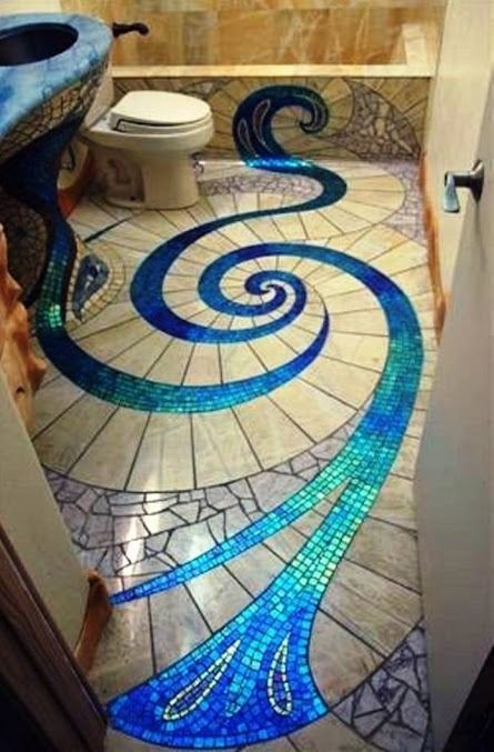 Bathroom with mosaic tile floor in a blue and teal wave design, alongside a blue sink and toilet.